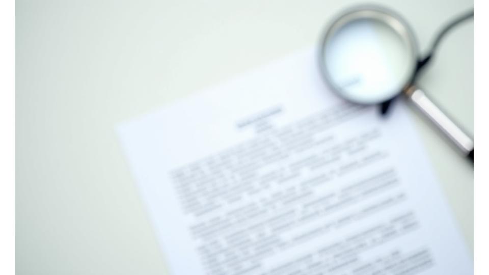 An open legal document with a magnifying glass, symbolizing clarity and transparency.